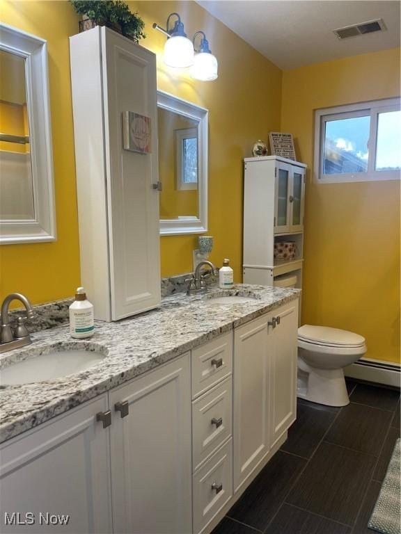 bathroom with vanity, toilet, and a baseboard heating unit