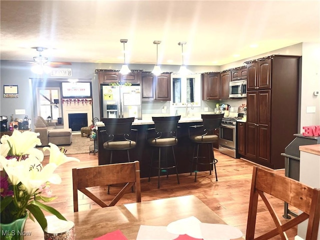 kitchen featuring hanging light fixtures, stainless steel appliances, a kitchen breakfast bar, dark brown cabinetry, and a kitchen island