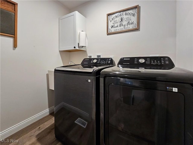 laundry room with cabinets, washer and dryer, and dark wood-type flooring