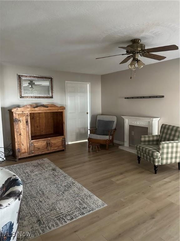 sitting room featuring ceiling fan, hardwood / wood-style floors, and a textured ceiling