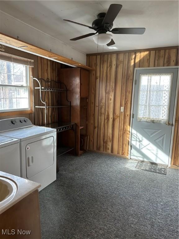 washroom with dark carpet, washer and clothes dryer, wooden walls, and ceiling fan