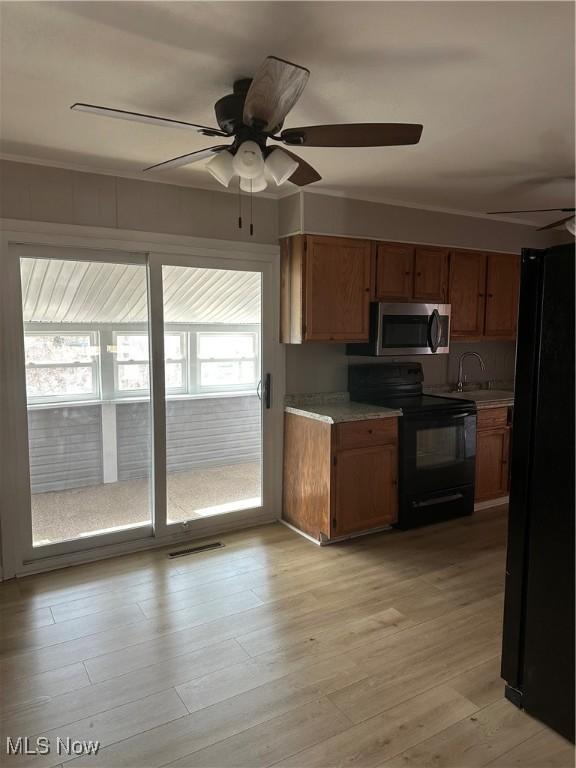 kitchen featuring sink, light hardwood / wood-style flooring, ceiling fan, and black appliances