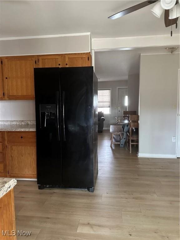 kitchen featuring ceiling fan, light hardwood / wood-style floors, and black refrigerator with ice dispenser