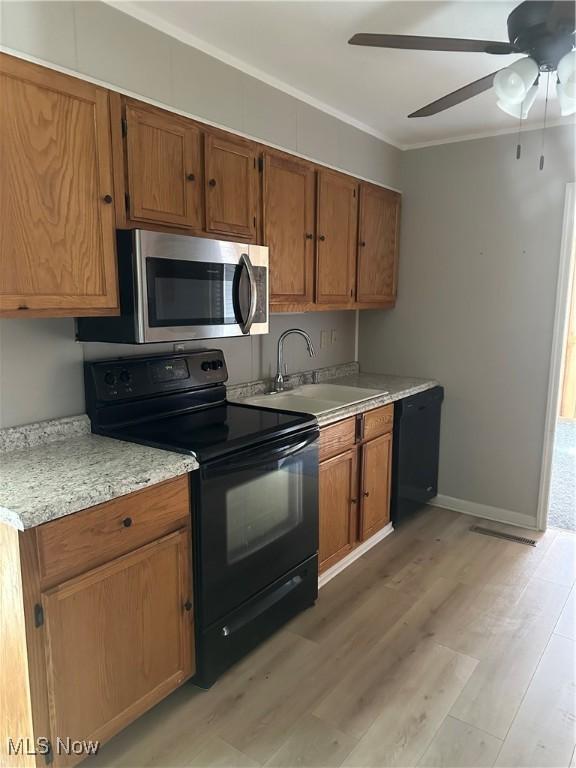 kitchen with sink, crown molding, light wood-type flooring, ceiling fan, and black appliances