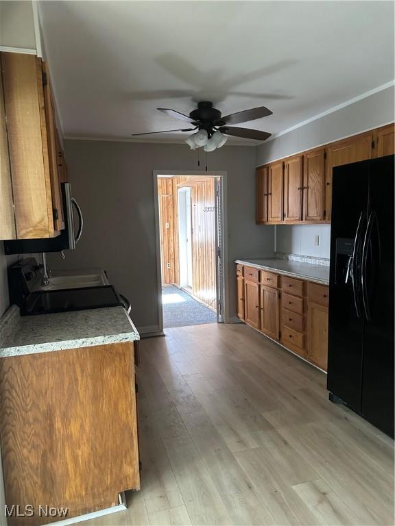 kitchen with stove, black fridge with ice dispenser, ceiling fan, and light wood-type flooring