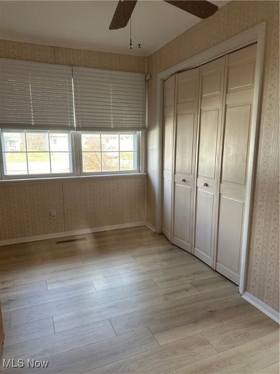 unfurnished bedroom featuring ceiling fan, light hardwood / wood-style floors, and a closet