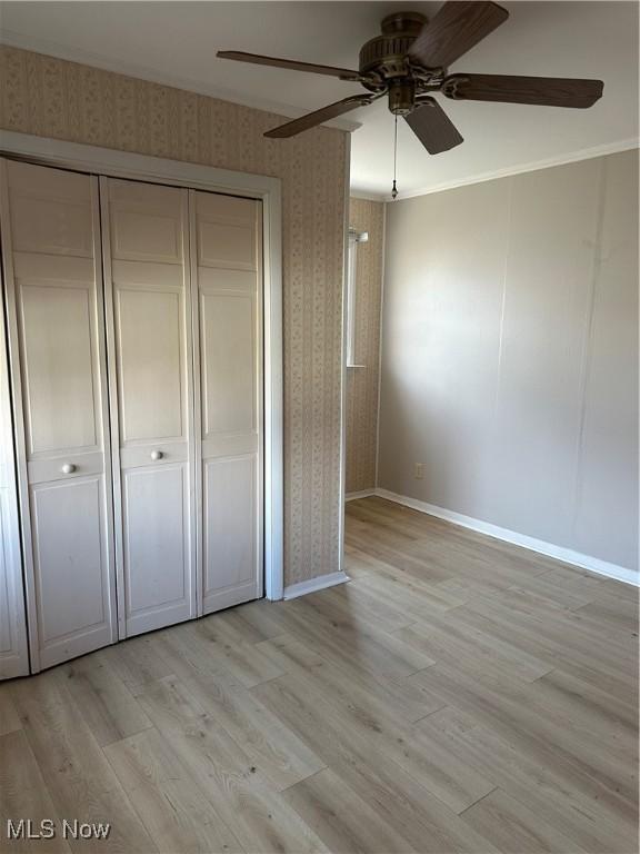 unfurnished bedroom with ceiling fan, a closet, ornamental molding, and light hardwood / wood-style flooring