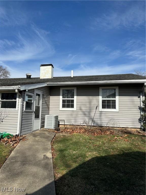 ranch-style home featuring cooling unit and a front lawn