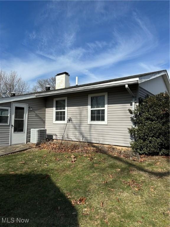 view of property exterior with a yard and central AC unit