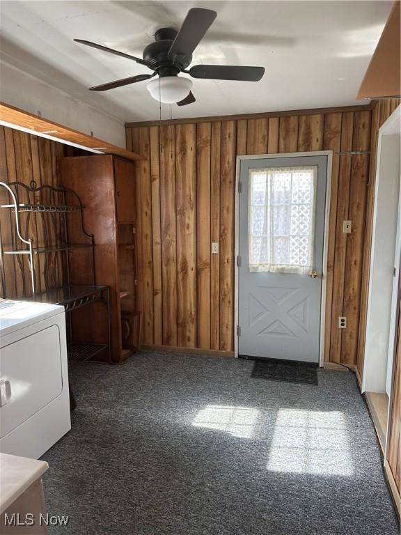 washroom with ceiling fan, wooden walls, washer / dryer, and dark colored carpet