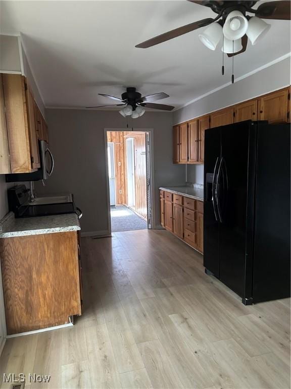 kitchen with ceiling fan, black fridge, range, and light wood-type flooring