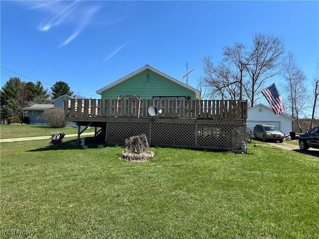back of property with a yard, a deck, and a detached garage