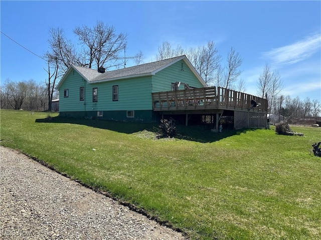 back of house featuring a lawn, a shingled roof, and a deck