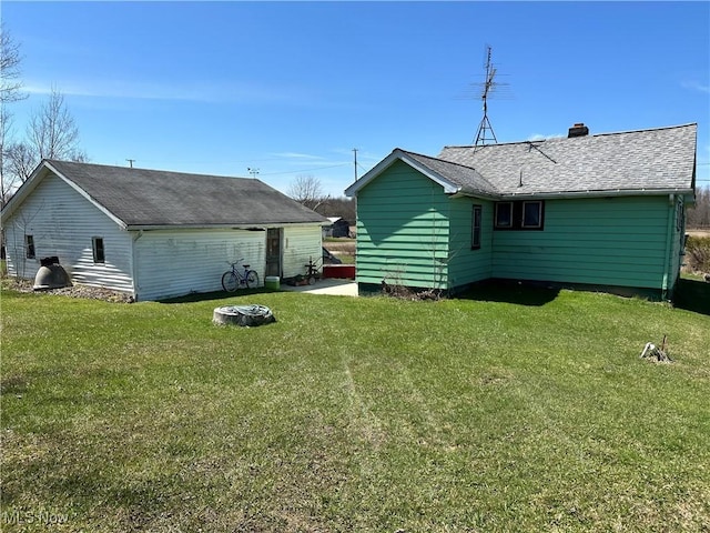 rear view of house with a lawn, a shingled roof, and a chimney