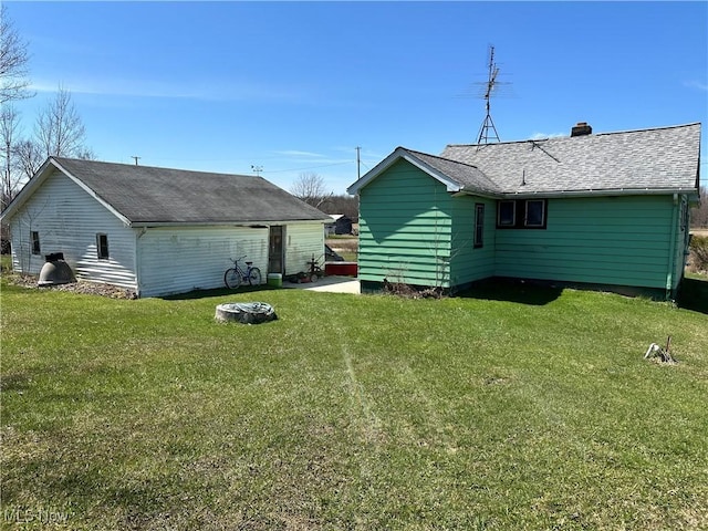 rear view of property with roof with shingles, a chimney, and a yard