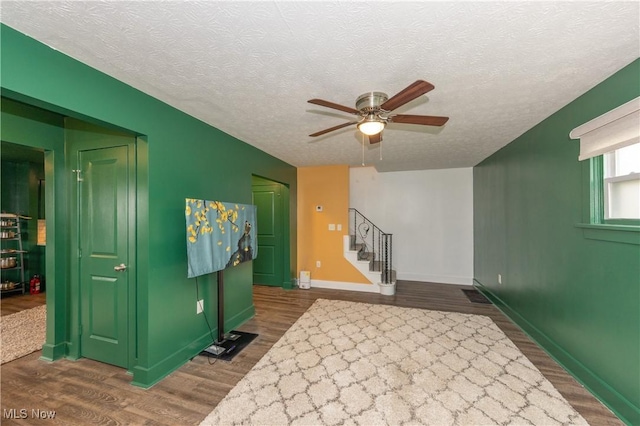 interior space with ceiling fan, dark hardwood / wood-style flooring, and a textured ceiling