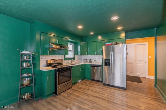 kitchen featuring appliances with stainless steel finishes, light hardwood / wood-style floors, sink, and decorative backsplash