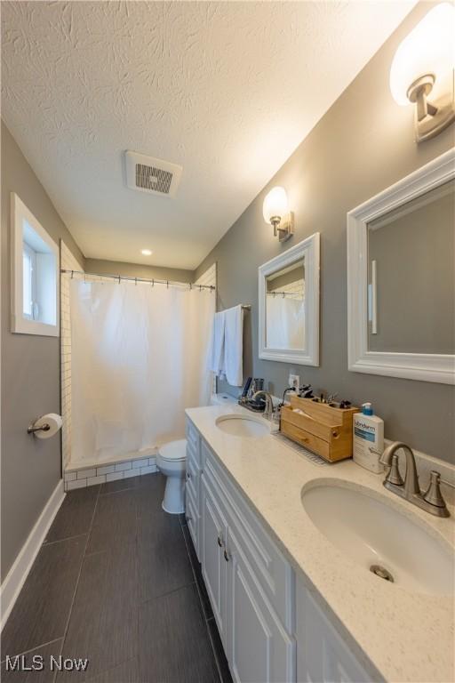 bathroom with vanity, curtained shower, a textured ceiling, and toilet