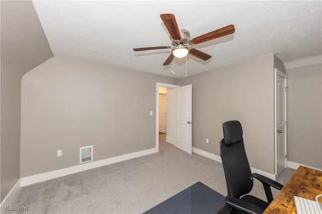 unfurnished office with light carpet, ceiling fan, and a textured ceiling