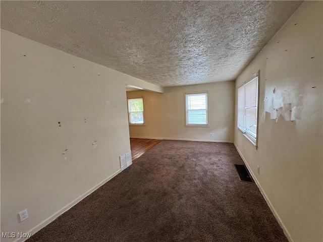 empty room with carpet and a textured ceiling