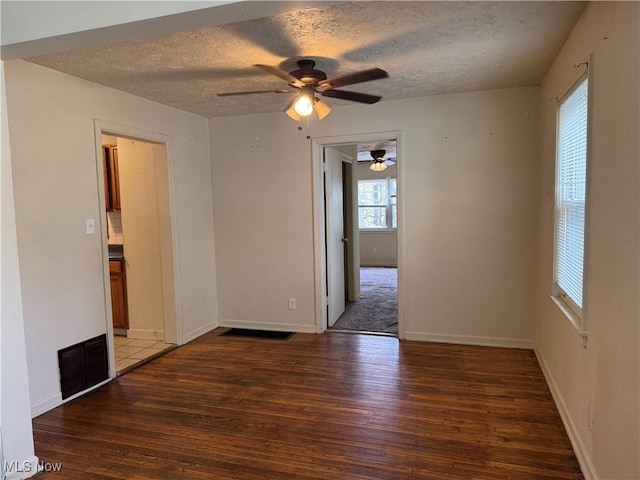 empty room with ceiling fan, dark hardwood / wood-style floors, and a textured ceiling