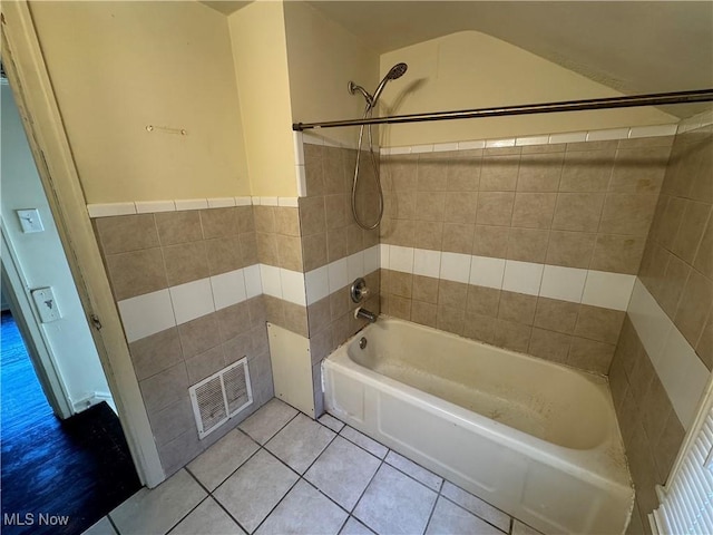 bathroom with tiled shower / bath combo, tile walls, and tile patterned floors