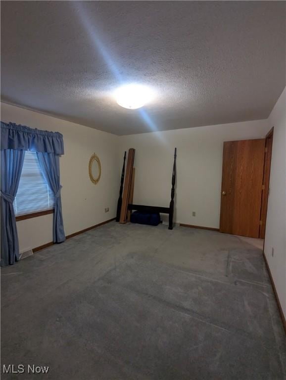 spare room featuring carpet floors and a textured ceiling