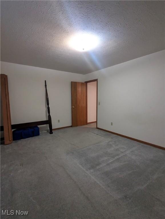 empty room with carpet floors and a textured ceiling