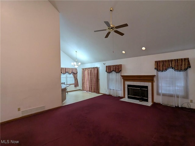 unfurnished living room with ceiling fan with notable chandelier, high vaulted ceiling, a tile fireplace, and light carpet