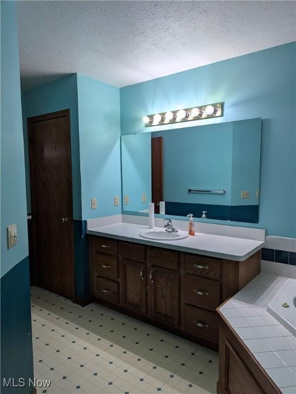 bathroom featuring vanity, a bathtub, and a textured ceiling