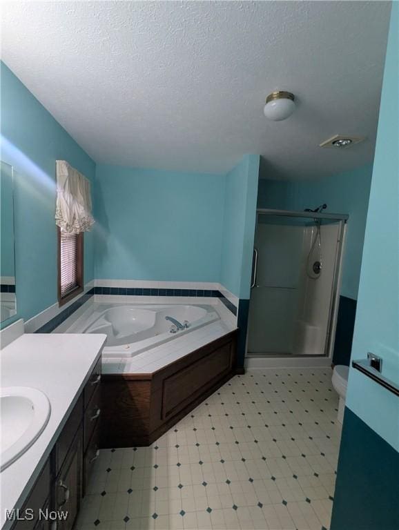 full bathroom featuring vanity, toilet, independent shower and bath, and a textured ceiling