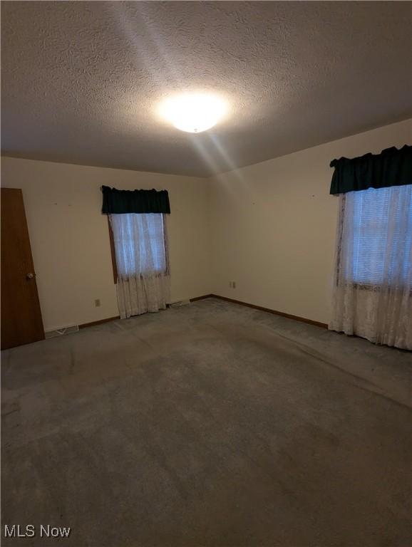 carpeted spare room featuring a textured ceiling