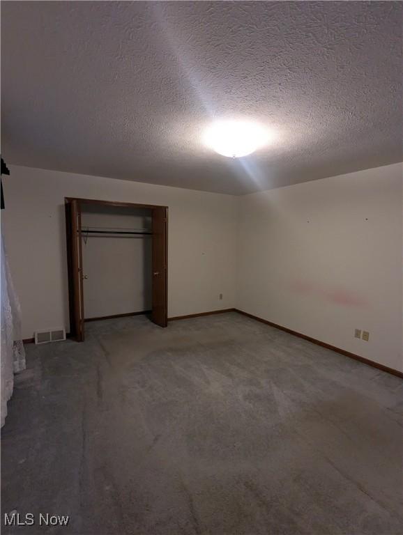 unfurnished bedroom with carpet floors, a textured ceiling, and a closet