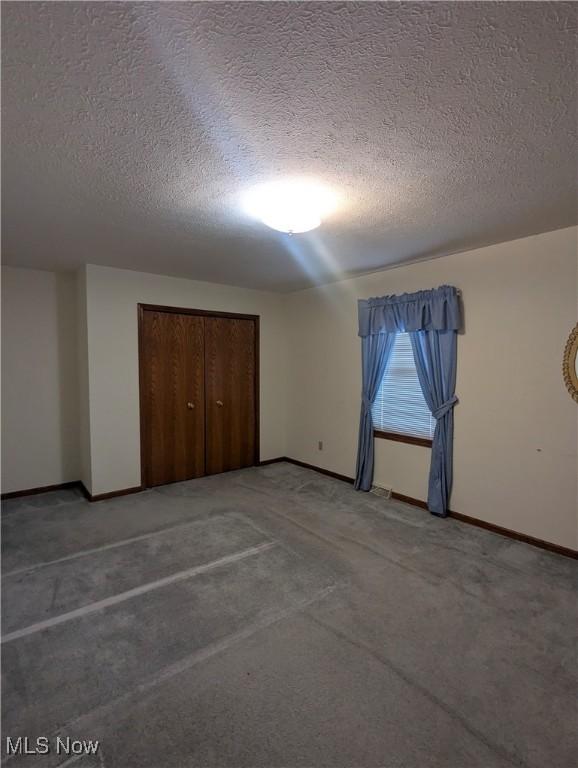 unfurnished bedroom with carpet, a textured ceiling, and a closet