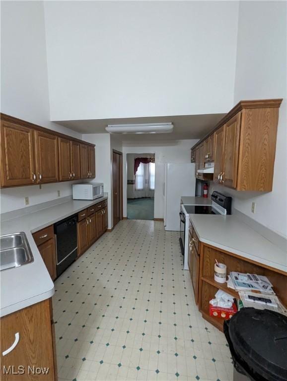 kitchen with a towering ceiling, black dishwasher, sink, and range with electric stovetop