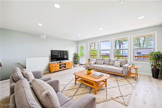 living room featuring a baseboard heating unit, a wealth of natural light, and light hardwood / wood-style flooring