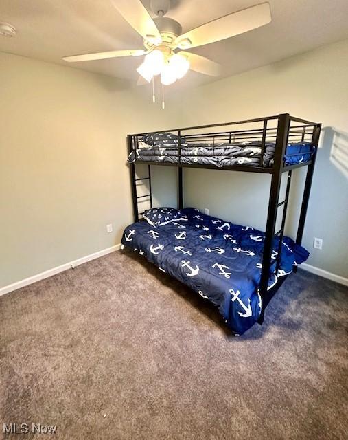 unfurnished bedroom featuring ceiling fan and dark colored carpet