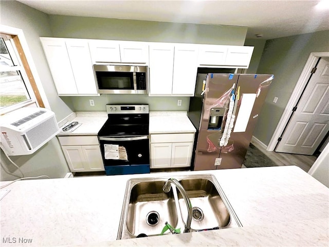 kitchen featuring white cabinetry, stainless steel appliances, sink, and an AC wall unit