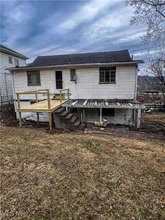 back of property featuring a deck and a lawn