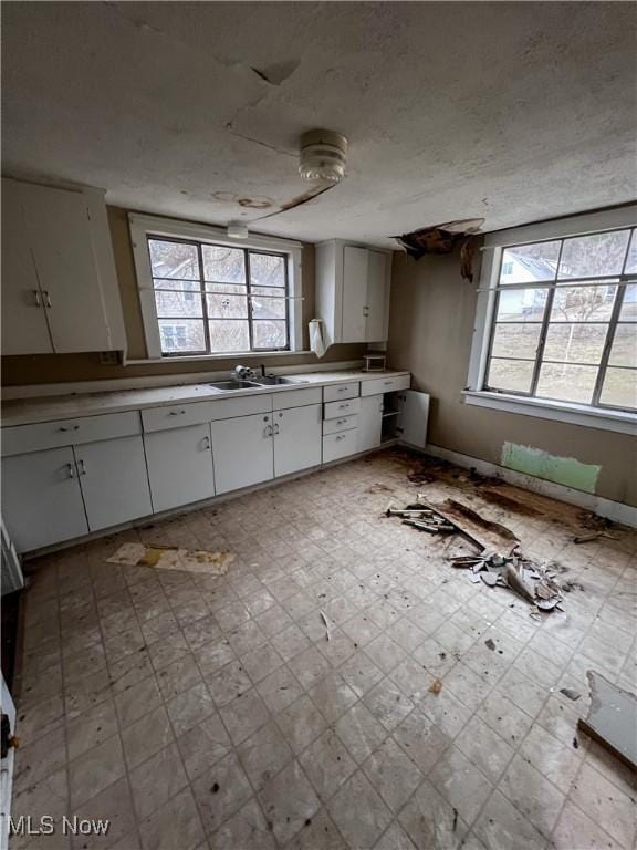 kitchen with white cabinetry, sink, and a textured ceiling