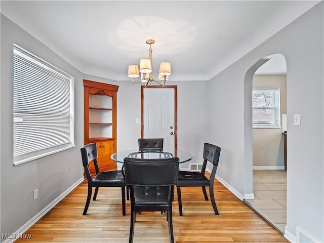 dining area with light hardwood / wood-style floors and a notable chandelier