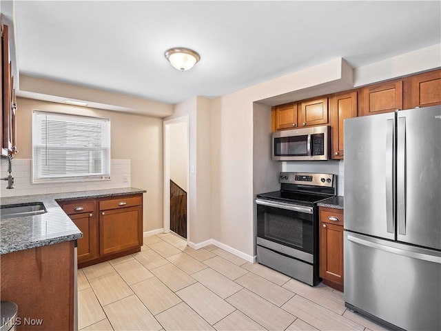 kitchen featuring backsplash, appliances with stainless steel finishes, sink, and dark stone countertops