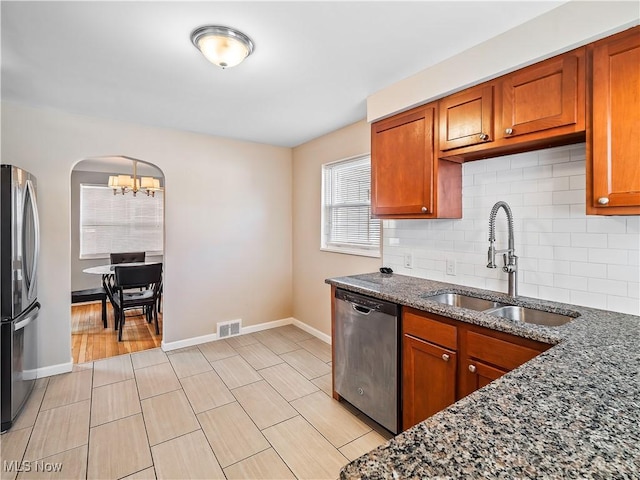 kitchen with tasteful backsplash, stainless steel appliances, sink, and dark stone counters