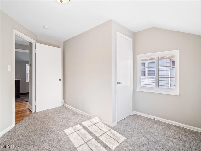 carpeted empty room featuring lofted ceiling and a healthy amount of sunlight