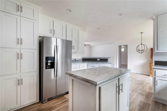 kitchen with a center island, stainless steel fridge with ice dispenser, hanging light fixtures, light wood-type flooring, and white cabinets