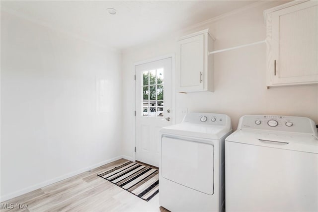 laundry room with cabinets, washing machine and dryer, and light hardwood / wood-style floors