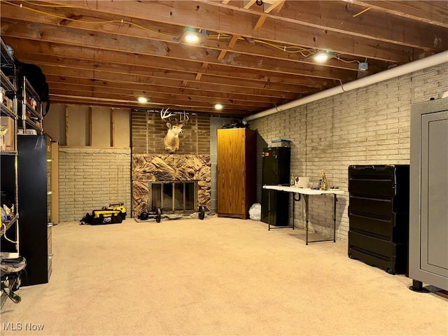 basement with light colored carpet, a large fireplace, and brick wall