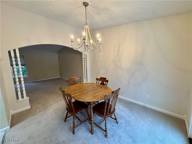 dining room with carpet floors, a textured ceiling, and a notable chandelier