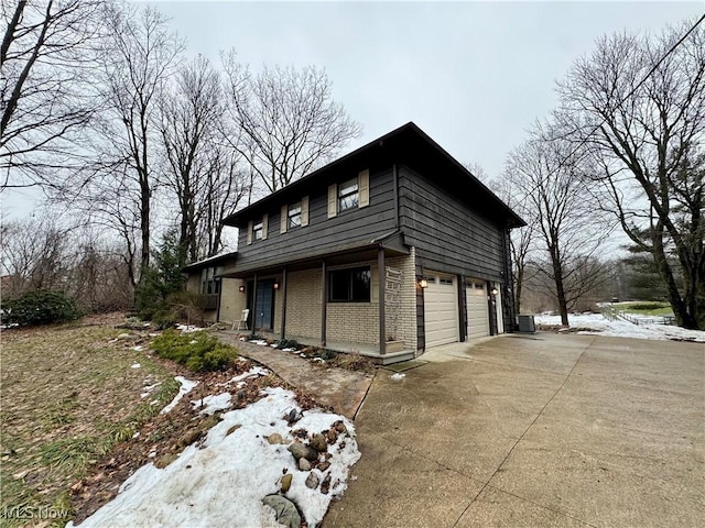 view of snow covered exterior with a garage and cooling unit