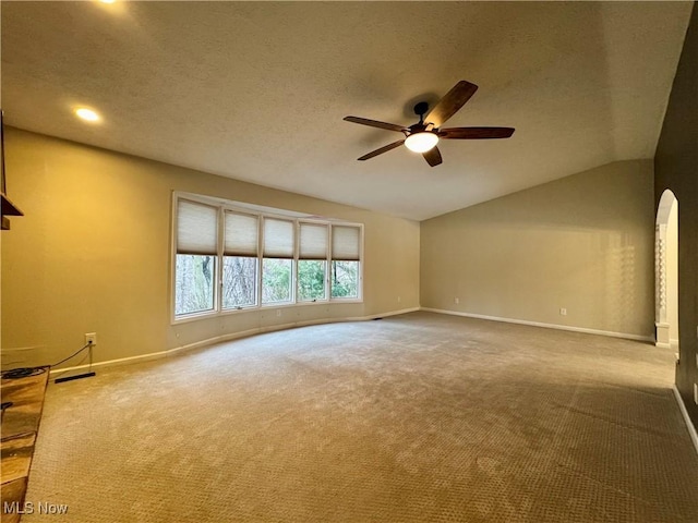 spare room featuring a textured ceiling, vaulted ceiling, ceiling fan, and carpet